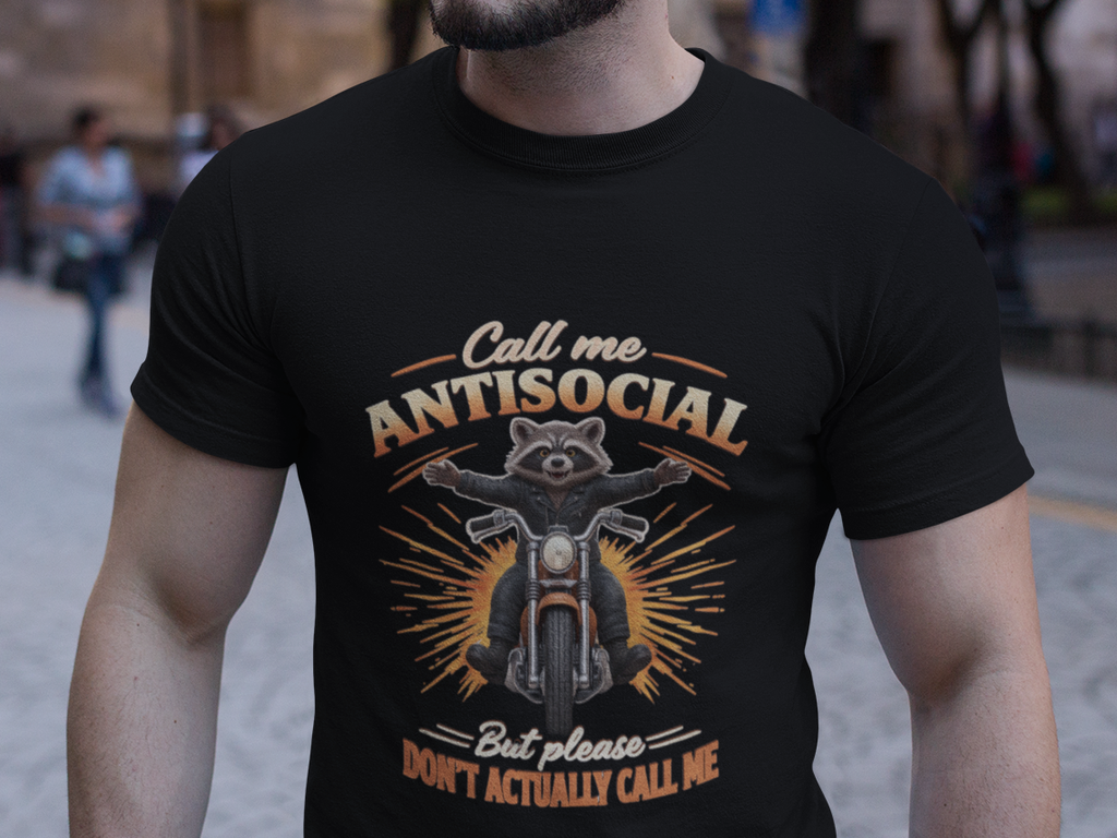 A man wearing a black graphic t-shirt with a motorcycle design and the text 'Call me ANTISOCIAL But please DON'T actually call me' standing on a city street at dusk.