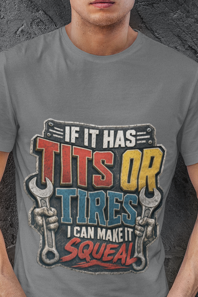 A man wearing a gray graphic t-shirt with a humorous slogan about tires and tools, posed against a dark textured wall.